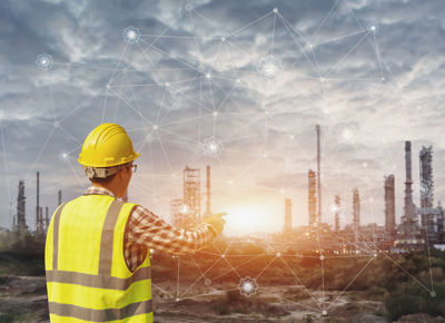 Industry worker pointing to ai generated network overlaying a industrial plant