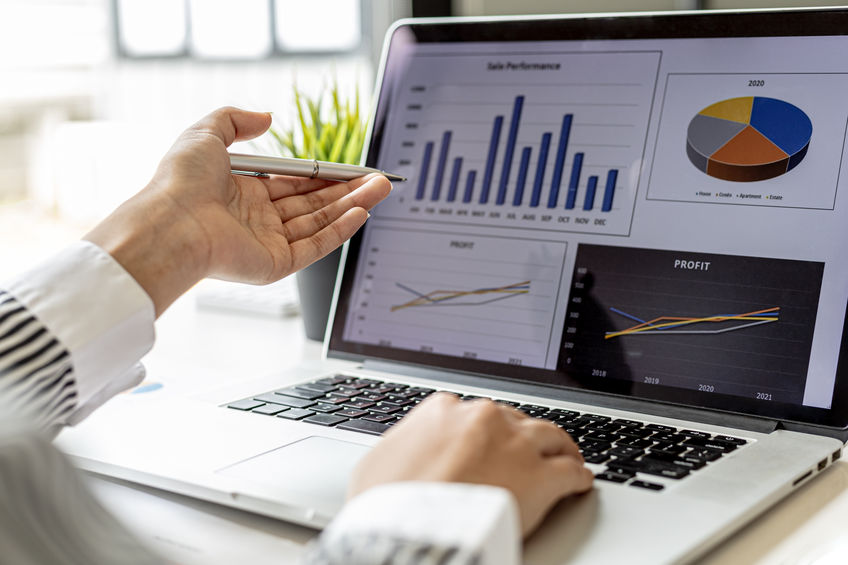 office worker with laptop pointing at screen with graphs on